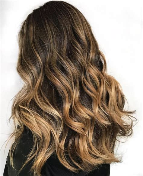 So, whether you are a dark brunette or have something closer to the mousy shade, you’ll definitely find a new interesting colormelt for your next salon visit. 1. Light Brown to Blonde Balayage for Shaggy Layers. 2. Dark Brown to Blonde Balayage with Black Roots. 3. Bronde Balayage with Well-Defined Highlights. 4.
